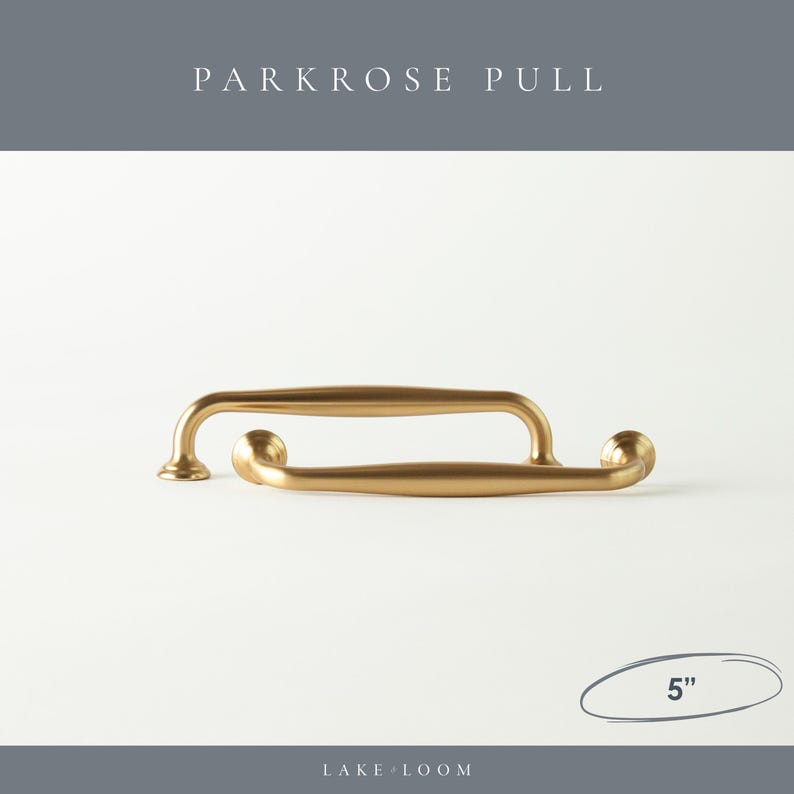 以下が含まれることがあります： 2つのゴールドカラーのParkroseプルハンドル。各約12.7cm。ハンドルは、丸みを帯びた端と中央のバーを備えた湾曲したデザインです。「PARKROSE PULL」の文字が上部に、「LAKE LOOM」の文字が下部にあります。