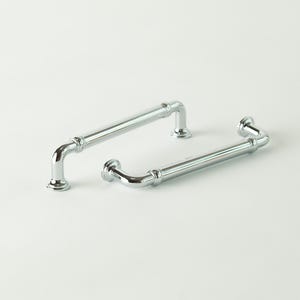 May include: Two polished chrome cabinet pulls on a white background. The pulls have a tubular design with curved ends and decorative circular bases. One pull is longer than the other.