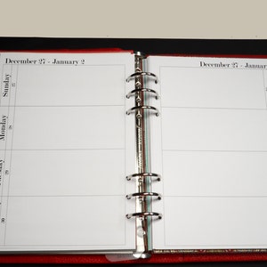May include: A white weekly planner with a red leather cover. The planner is open to the week of December 27th to January 2nd. The planner has a column for each day of the week, with space for notes.