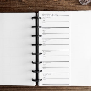 May include: A white planner with a black spiral binding. The planner has a section labeled "Appointments" with lines for writing down where, who, date, time, and notes.