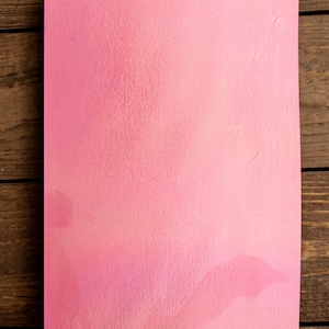 May include: A pink, textured, rectangular piece of paper.