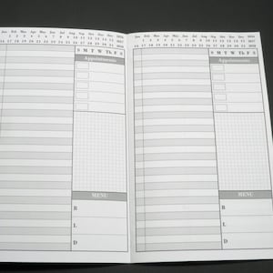 May include: A black and white planner with a monthly calendar and daily schedule sections. The planner has a grid for notes and a menu section for meal planning.