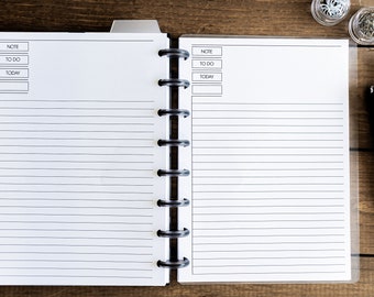 Op de afbeelding: Een wit, gestreept, spiraalgebonden notitieboek met een zwarte omslag. Het notitieboek heeft secties met de labels "Notitie", "Te doen" en "Vandaag".