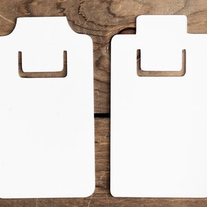 May include: Two white cardboard clipboard style tags with a cut-out handle. The tags are blank and ready to be written on.