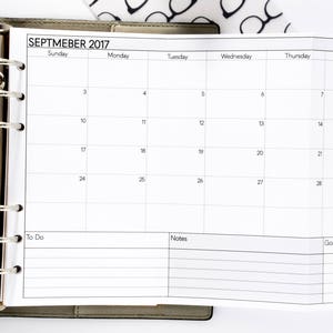 May include: A white monthly planner with a brown leather binder. The planner has a tab for September 2017 and includes sections for To Do, Notes, and Goals.