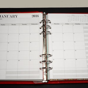 May include: A white monthly planner with a red cover and silver rings. The planner is open to January 2016 and has a notes section, a calendar grid, and a to-do list.