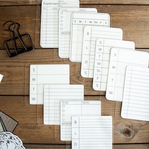 May include: A set of eight white printable planner cards with black lines and text. The cards include "Expenses", "To Do", "Notes", and a weekly calendar.