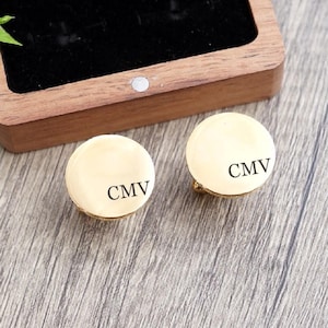 May include: Two gold cufflinks with a round shape and the initials "CMV" engraved on each. The cufflinks are in a wooden box.