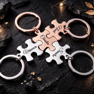 May include: A collection of personalized puzzle piece keychains. The keychains are in silver and rose gold tones, each engraved with a name. The keychains are connected, symbolizing unity. The background is dark with decorative elements.