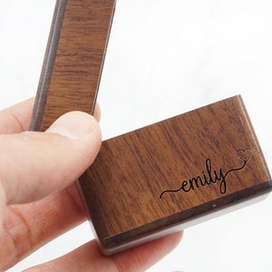 Peut inclure: Une bo&icirc;te &agrave; bague en bois avec le nom "emily" grav&eacute; sur le couvercle, ainsi qu'un petit symbole de c&oelig;ur.