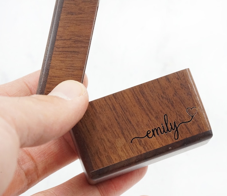 Peut inclure: Une bo&icirc;te &agrave; bague en bois avec le nom "emily" grav&eacute; sur le couvercle, ainsi qu'un petit symbole de c&oelig;ur.
