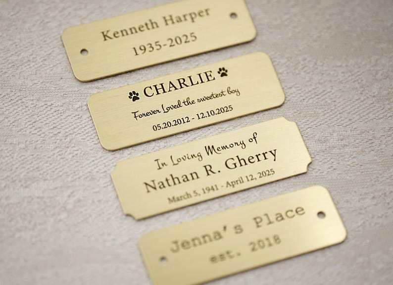 May include: Four rectangular brass nameplates with engraved text. The plates include names, dates, and phrases like "Forever Loved the sweetest boy" and "In Loving Memory of." One plate is for "Jenna's Place, est. 2018."