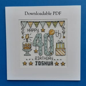 Peut inclure: Carte de vœux de 40e anniversaire brodée au point de croix avec le texte "Happy 40th Birthday Joshua". La carte présente un gâteau, des cadeaux, des étoiles et des guirlandes aux tons de bleu, jaune et vert. Le texte "Downloadable PDF" est en haut.