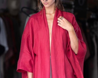 May include: A red linen kimono with long sleeves and a wide open front. The kimono is made of a soft, lightweight fabric and has a relaxed fit.