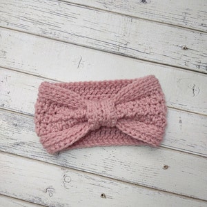 May include: A pink knitted headband with a bow detail. The headband is made of soft yarn and is perfect for keeping your ears warm in the winter.