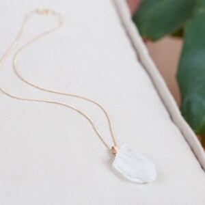 May include: A gold chain necklace with a clear, faceted crystal pendant.