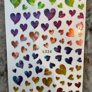 Peut inclure: Une feuille d'autocollants en forme de cœur irisés de différentes couleurs, notamment le vert, le violet, le bleu, l'orange et le rouge. La feuille est étiquetée "L024".