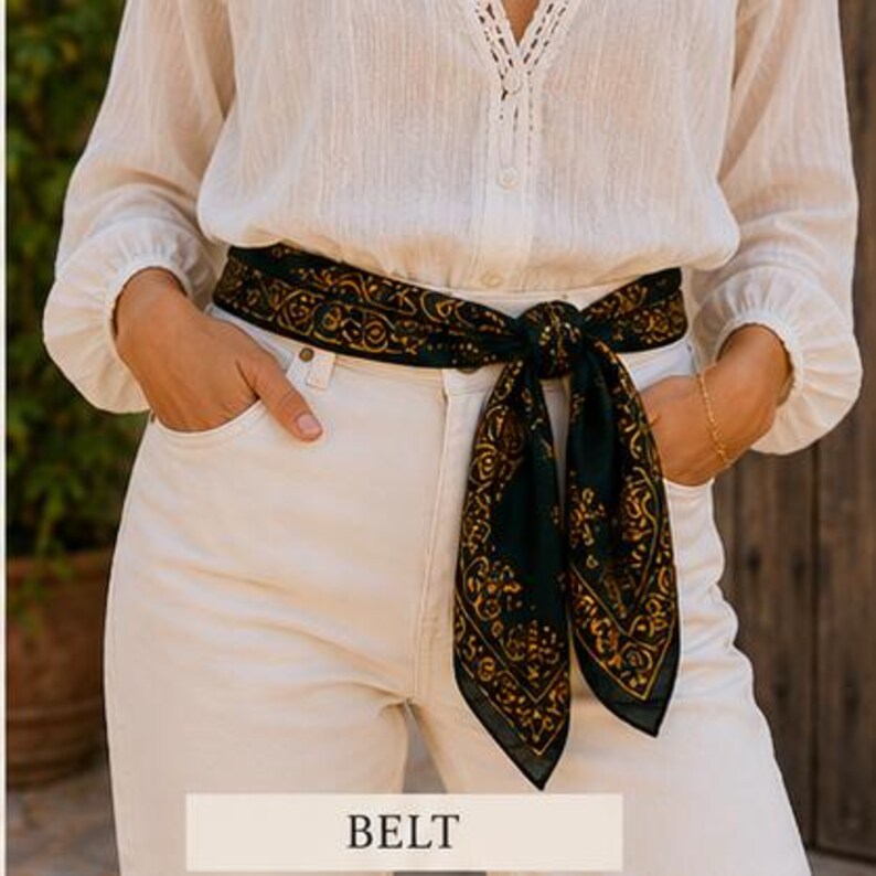May include: A dark green belt with a gold paisley design is tied around the waist. The belt is worn over white pants and a white blouse. The word "BELT" is displayed in a white rectangle at the bottom of the image.
