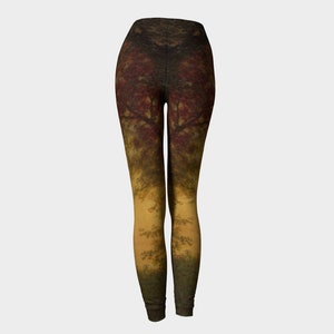 May include: A pair of leggings featuring a colourful autumnal forest scene printed on them. The leggings are a dark brown colour with a gradient of yellow and green at the bottom.