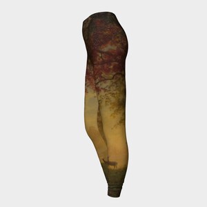May include: A pair of leggings featuring a nature scene print. The design depicts a deer standing in a woodland setting with trees and foliage in shades of red, orange, and yellow.