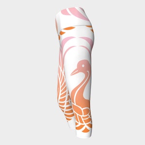 K&ouml;nnte beinhalten: Wei&szlig;e Yoga-Leggings mit einem pink-orangenen Farbverlaufsmuster, das einen stilisierten Kranich mit ausgebreiteten Fl&uuml;geln zeigt.