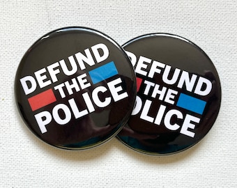 May include: Two black button pins with the text "DEFUND THE POLICE" in white letters. The text is separated by a red and blue stripe.