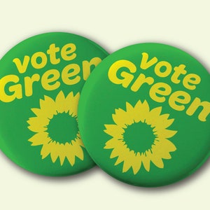 May include: Two green round buttons with the text "Vote Green" in yellow letters. Each button has a yellow stylized sunflower in the center.