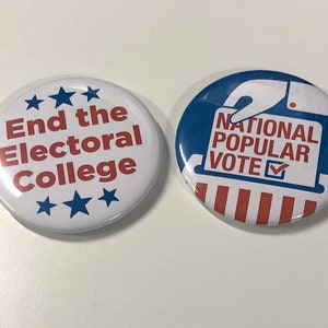 May include: Two round buttons with political messages. The first button is white with blue stars and red text that says "End the Electoral College". The second button is blue with a white hand holding a ballot that says "National Popular Vote" with a checkmark. The ballot is on top of red and white stripes.