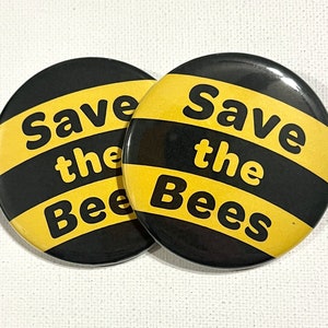 May include: Two black and yellow round buttons with the text "Save the Bees" in white.