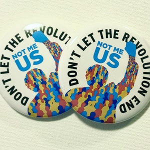 May include: Two white round buttons with black text that reads "Don't Let The Revolution End Not Me Us". The buttons feature a graphic of a crowd of people with a raised fist.