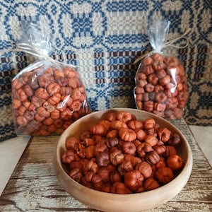May include: Three bags of dried orange pumpkin potpourri, two in clear plastic bags tied with twine, and one in a wooden bowl. The bags and bowl are on a rustic wooden surface.