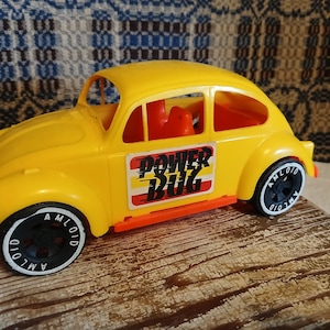 May include: Yellow toy car with black wheels and the words "Power Bug" on the side. The car has a red stripe along the bottom.