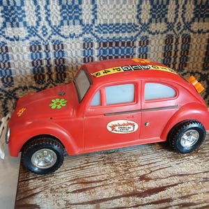 May include: Red toy car with a "Sparkling Engine" sticker and a flower sticker. The car has a black and white checkered stripe on the roof and a number sticker on the side.
