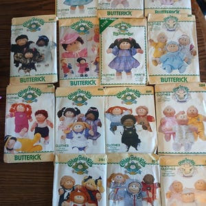 May include: A collection of fourteen Butterick sewing patterns for Cabbage Patch Kids dolls, each featuring illustrations of dolls in various outfits, with brand logos and pattern numbers printed on the white paper envelopes.