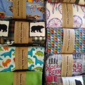 May include: A collection of reusable baby wipes and toilet paper squares with various colorful patterns. The patterns include dinosaurs, trucks, bears, and dreamcatchers. The squares are labeled with the text "Reusable Baby Wipe" and "Reusable Toilet Paper".