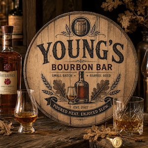 May include: A wooden bourbon barrel head sign with the text "YOUNG'S BOURBON BAR" and the words "SMALL BATCH" and "BARREL AGED". A bottle of Four Roses bourbon and two glasses of bourbon are in the foreground.