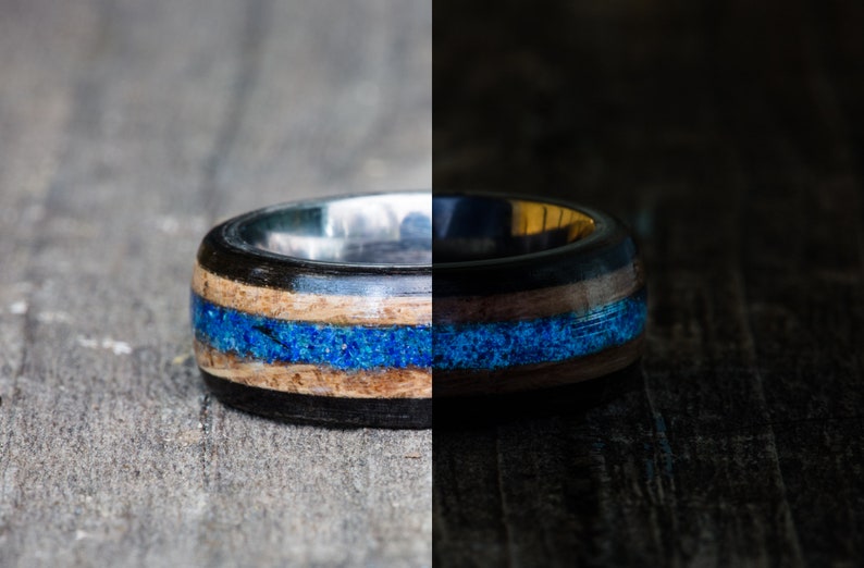 May include: A close-up of a wooden ring with a blue inlay. The ring is made of dark wood and has a silver band.
