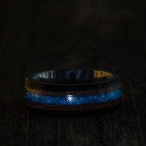 May include: A dark wood ring with a blue and gold inlay. The ring is made of wood and has a smooth finish.