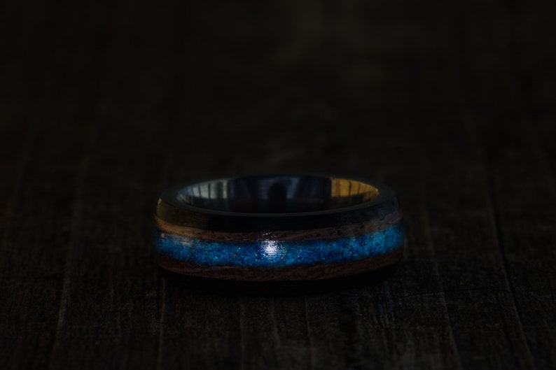May include: A dark wood ring with a blue and gold inlay. The ring is made of wood and has a smooth finish.