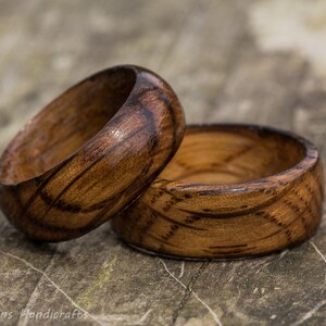 May include: Two wooden rings with a dark brown wood grain and a light brown wood grain. The rings are stacked on top of each other.