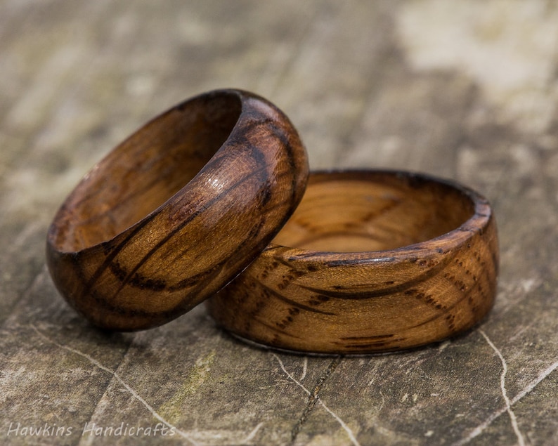 May include: Two wooden rings with a dark brown wood grain and a light brown wood grain. The rings are stacked on top of each other.