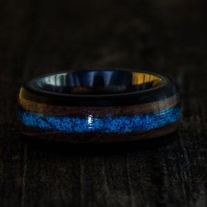 May include: A dark blue and brown wooden ring with a thin blue inlay. The ring is made of wood and has a polished finish.