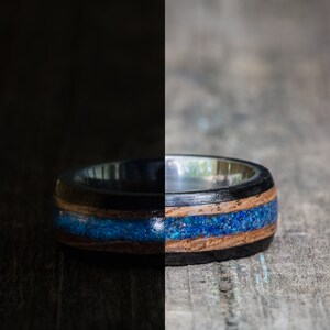 May include: A black and brown wooden ring with a blue inlay. The ring is made of wood and has a silver band.