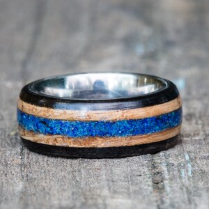 May include: A wooden ring with a blue inlay and a silver band.