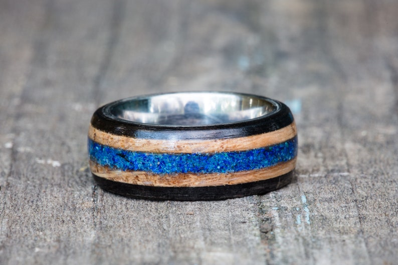 May include: A wooden ring with a blue inlay and a silver band.