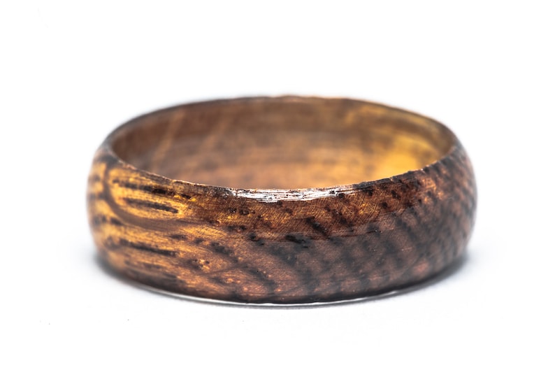 May include: A dark brown wooden ring with a natural wood grain pattern. The ring has a smooth, polished finish.