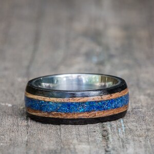 May include: A wooden ring with a blue and brown inlay and a silver band.