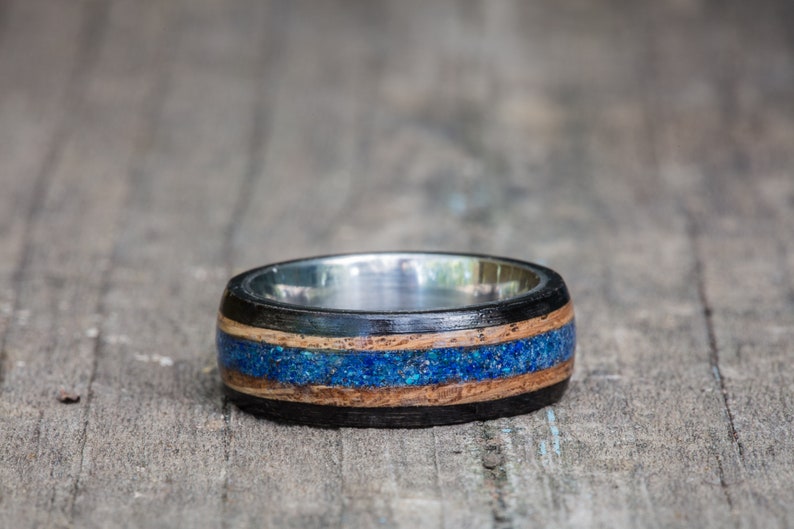 May include: A wooden ring with a blue and brown inlay and a silver band.