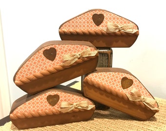 May include: Four decorative wooden boxes with a pie-shaped design. Each box features a peach-colored patterned top, a brown heart accent, and a jute bow. The boxes are stacked, showcasing their unique design and rustic charm.