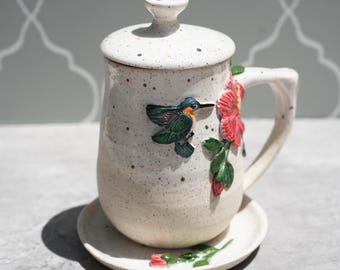 Handgemaakte kolibrie-hibiscusmok met deksel en schotel: theekop van aardewerk bloemen